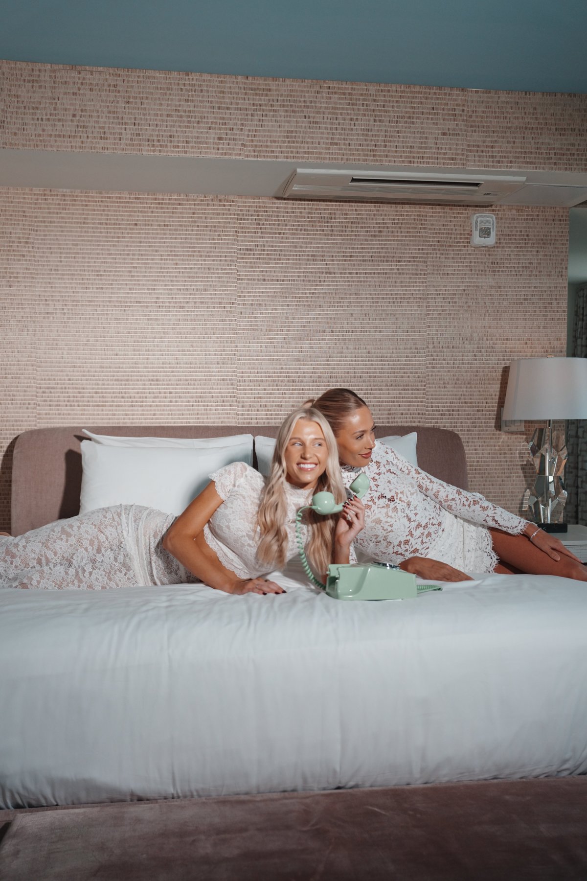 Two creators in white lace on the bed with a green phone